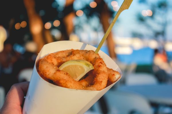 calamari-in-a-takeaway-paper-cup-eating-from-food-trucks-in-the-evening-at-a-music-festival_t20_eVNvN7